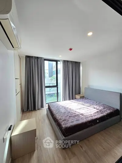Bright and modern bedroom with large window and stylish furnishings in a contemporary apartment.