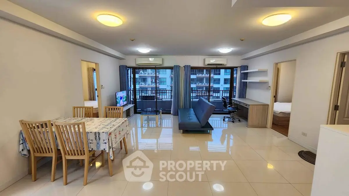 Spacious open-plan living room with dining area and balcony view in modern apartment.