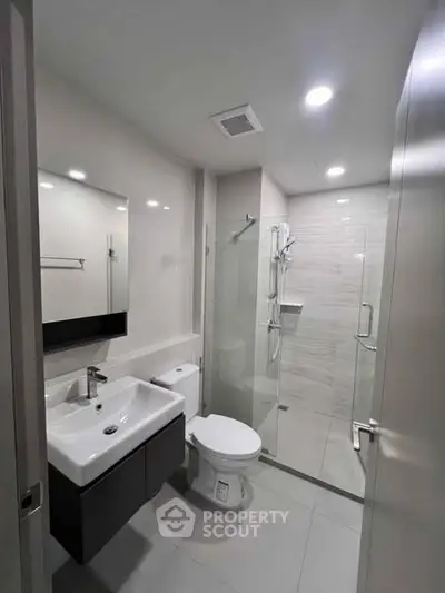 Modern bathroom with sleek fixtures and glass shower enclosure in a contemporary apartment.