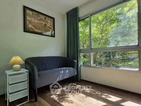Bright living room with large window and cozy seating area, perfect for relaxation.