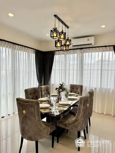 Elegant dining room with plush chairs and modern chandelier in a bright, airy space.