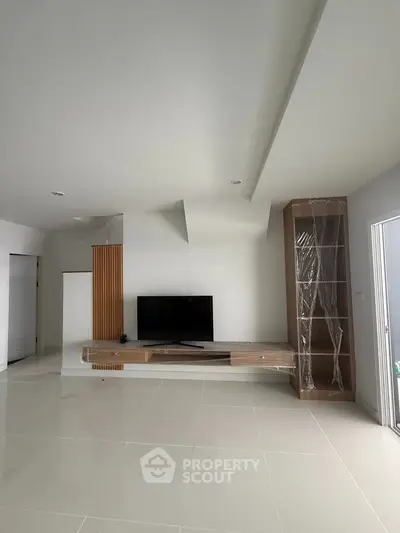 Spacious modern living room with sleek TV stand and minimalist design, perfect for contemporary living.