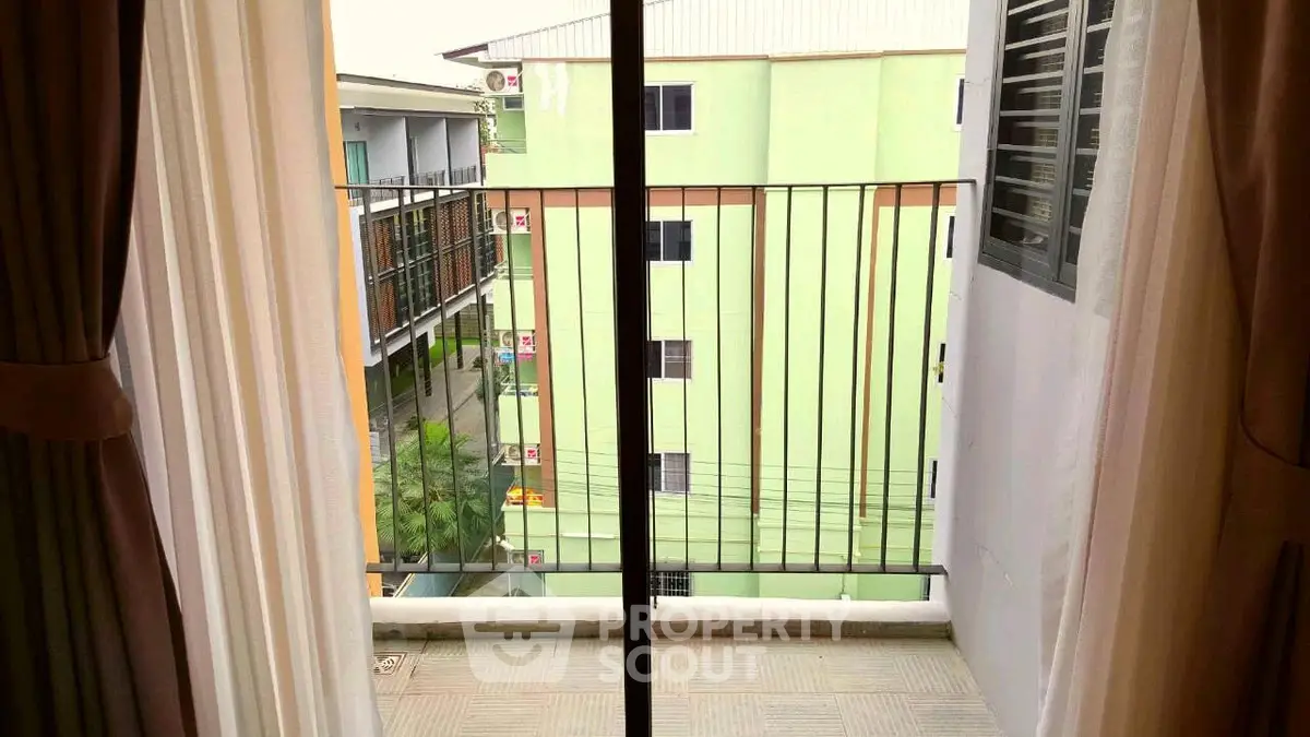 Charming balcony view with sliding glass doors and urban surroundings, perfect for city living.