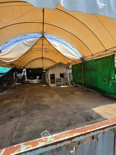 Spacious covered outdoor area with canopy and small structure, ideal for storage or events.