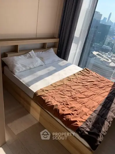 Modern bedroom with city view, featuring a cozy bed and large windows for natural light.