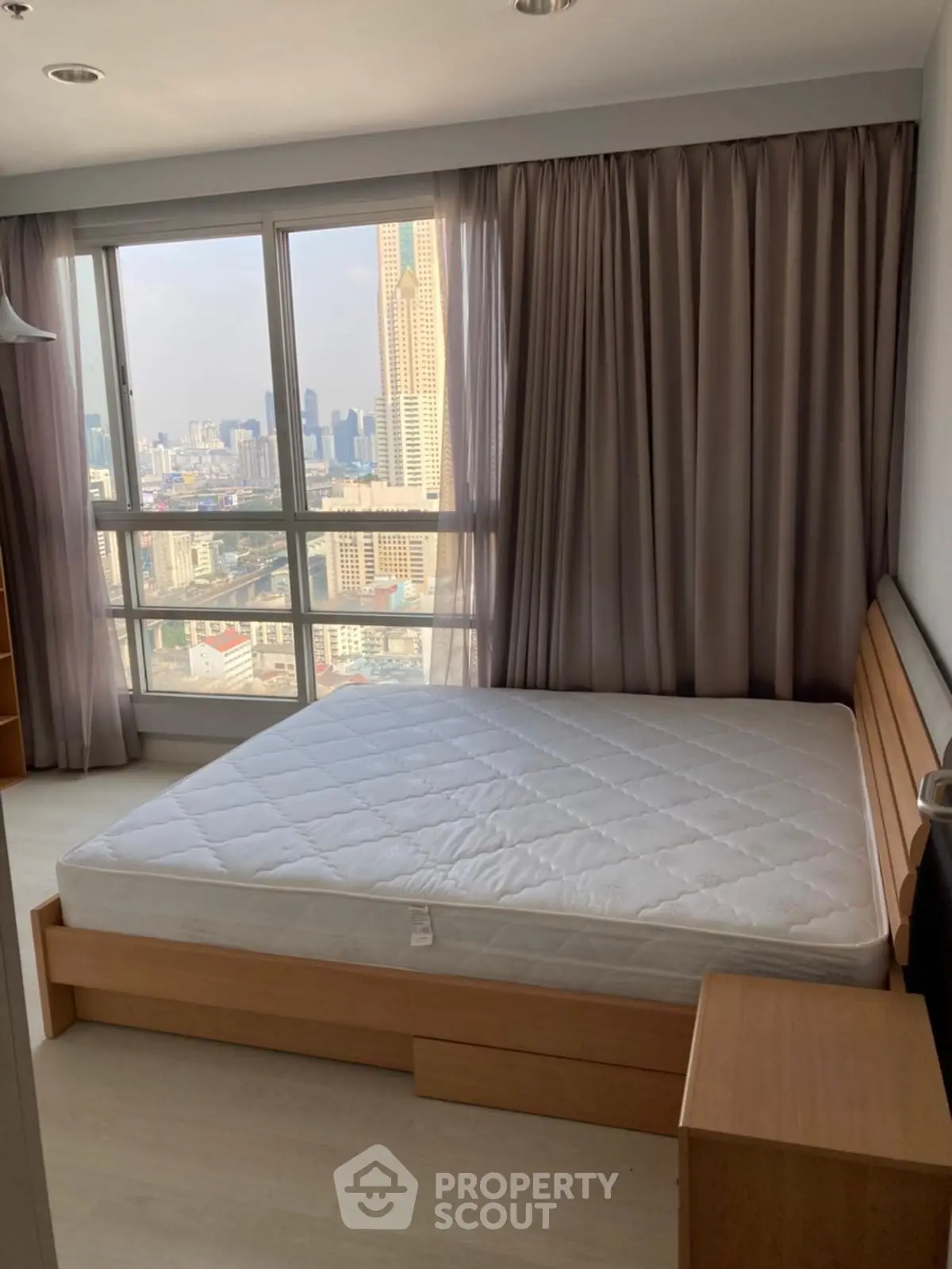 Spacious bedroom with city view and large windows in modern apartment