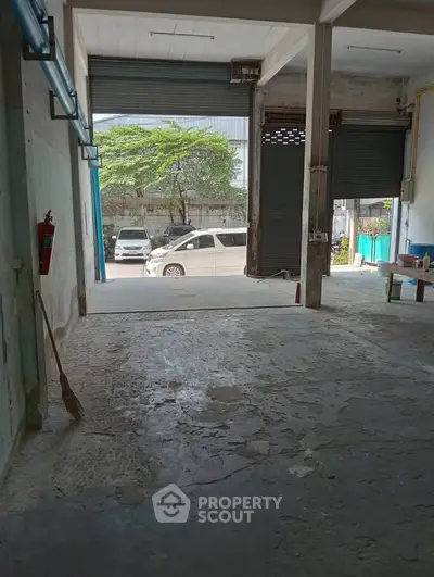 Spacious industrial warehouse with large open entrance and ample parking space.