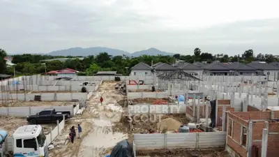 Expansive construction site with developing residential homes and scenic mountain backdrop.