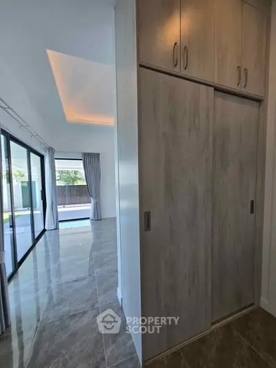 Spacious modern living room with sliding glass doors and built-in storage, featuring elegant flooring.