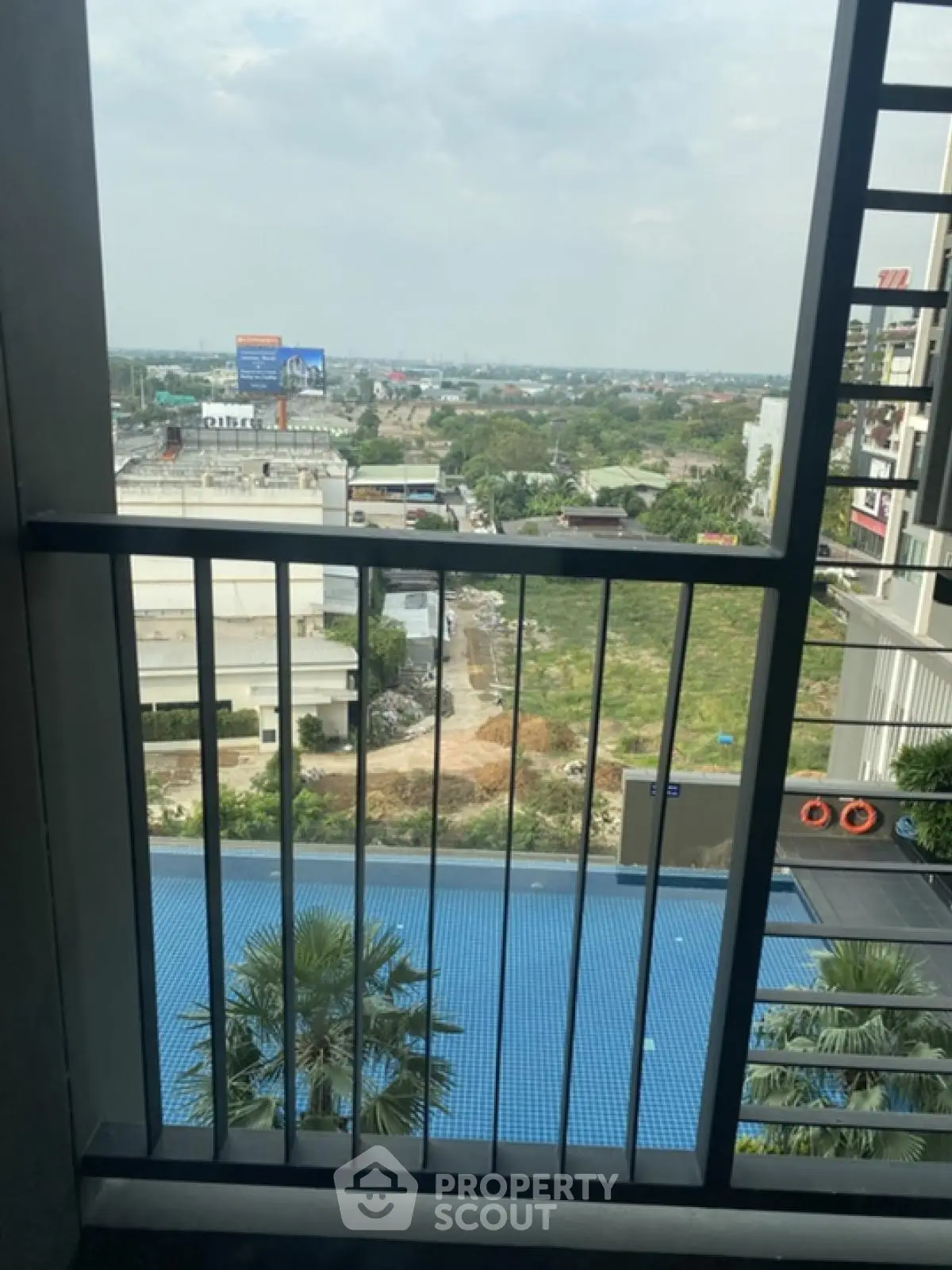 Stunning balcony view overlooking a serene pool and lush greenery, perfect for relaxation.