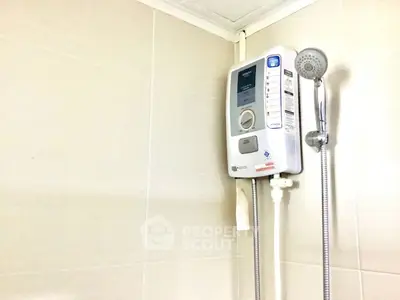 Modern bathroom with sleek electric shower unit and handheld showerhead.