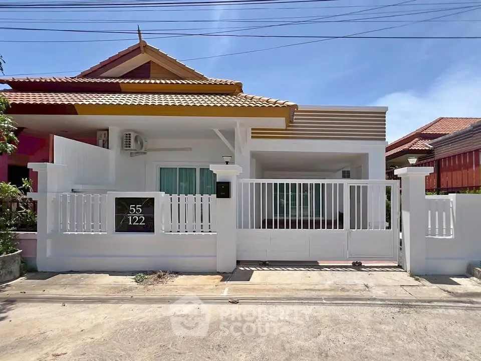 Charming single-story house with modern facade and gated entrance in a sunny neighborhood.