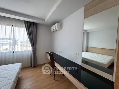 Modern bedroom with large window, wooden flooring, and sleek furniture in a bright apartment.