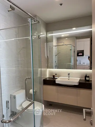 Modern bathroom with glass shower and sleek vanity in a contemporary apartment.
