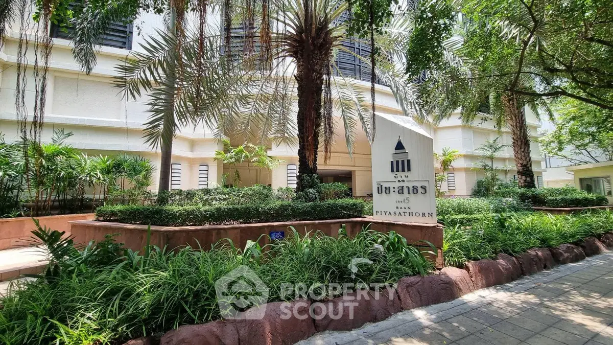 Elegant entrance of a modern building surrounded by lush greenery in a prime location.