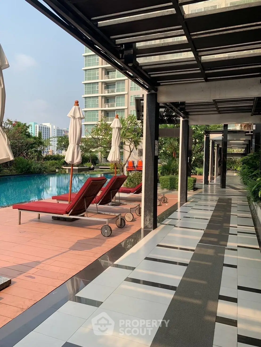 Luxurious poolside area with sun loungers and modern architecture in a high-rise building complex.