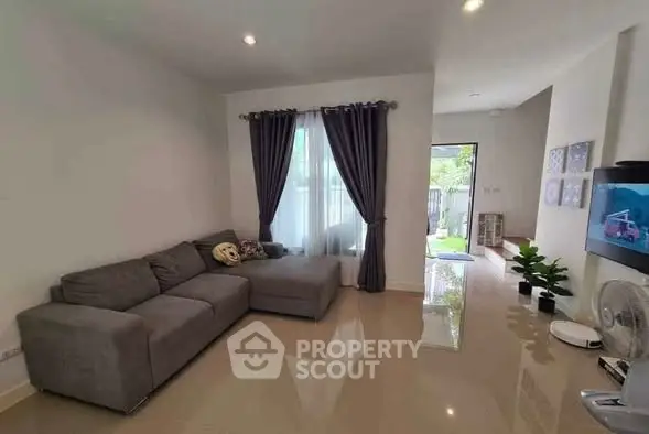 Modern living room with gray sectional sofa and large window with curtains.
