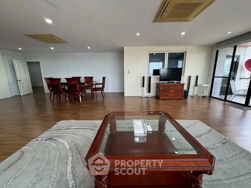 Spacious living room with elegant wooden furniture and large windows for natural light.