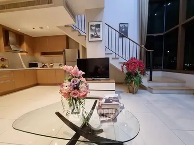 Luxurious modern living room with open kitchen and elegant staircase, perfect for stylish urban living.