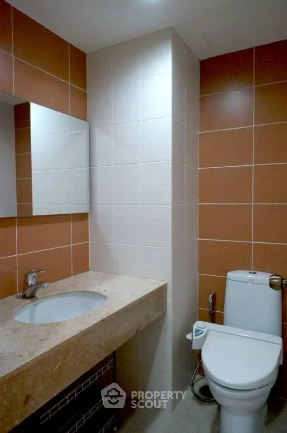 Modern bathroom with sleek design and tiled walls, featuring a stylish sink and toilet.