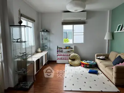 Charming living room with wooden floors, cozy sofa, and display shelves, perfect for relaxation and family time.