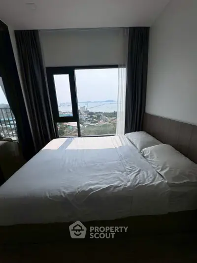 Stunning bedroom with panoramic sea view from large window, perfect for serene living.
