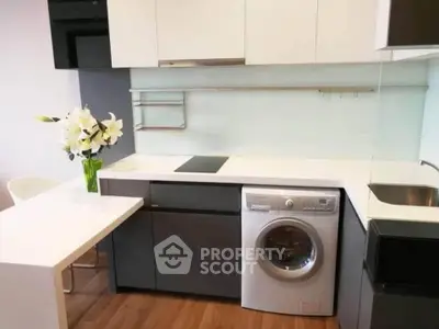 Modern kitchen with sleek cabinetry and built-in washing machine, featuring a minimalist design and elegant decor.
