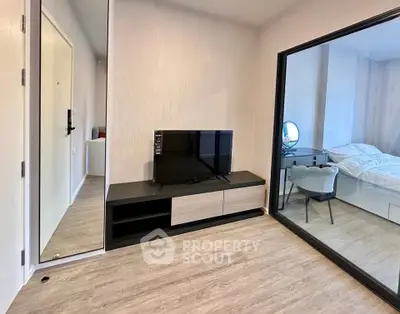 Modern living room with sleek TV stand and view into cozy bedroom