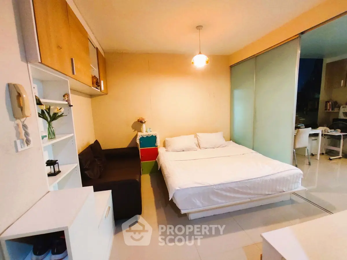 Cozy bedroom with modern decor and sliding glass doors in a compact apartment.