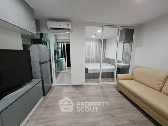 Modern apartment with open layout, featuring a cozy living area and a glimpse of the bedroom.