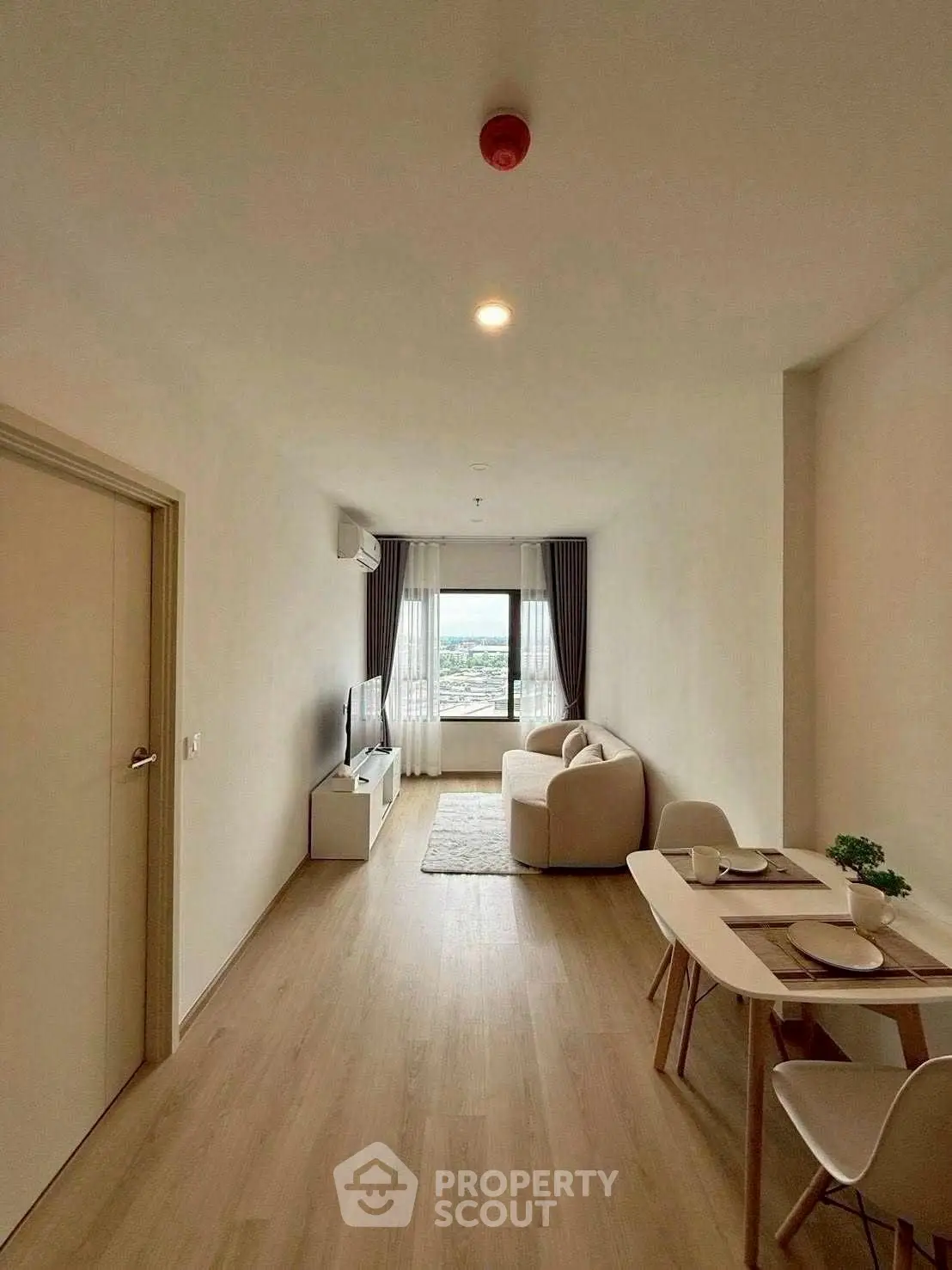 Modern living room with cozy sofa, dining table, and city view window.