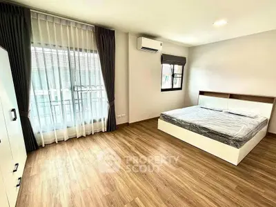Spacious modern bedroom with wooden flooring and large windows