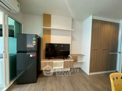 Modern living room with sleek TV setup and stylish fridge in a cozy apartment.