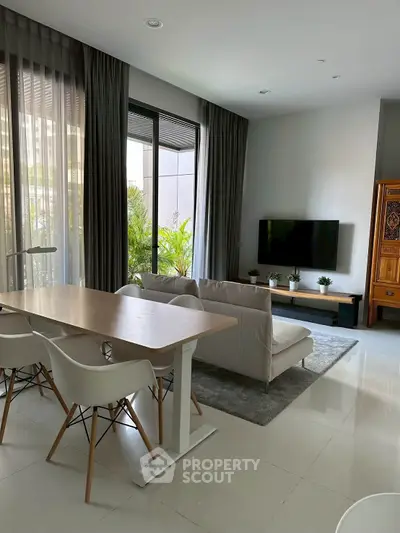Modern living room with stylish furniture and large windows offering natural light and garden view.