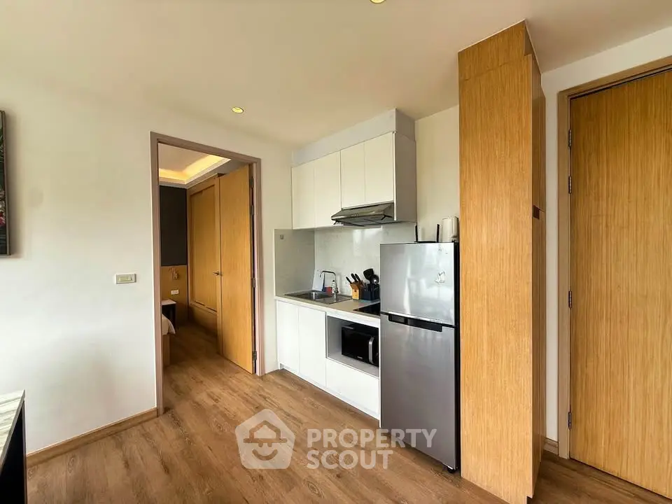 Modern kitchen with sleek appliances and wooden flooring in a cozy apartment setting.