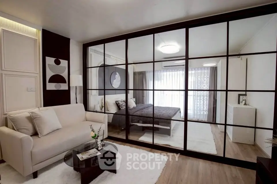 Modern studio apartment with glass partition, cozy living area, and stylish bedroom.