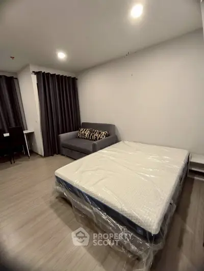 Modern bedroom with cozy bed and stylish sofa in a well-lit apartment.