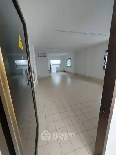 Spacious empty room with tiled flooring and ample natural light, ideal for customization.