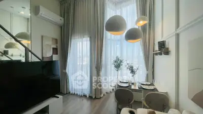 Modern living room with high ceilings, elegant lighting, and large windows offering a stunning city view.