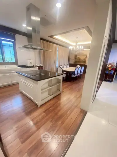Luxurious open kitchen and dining area with elegant wood flooring and modern island.