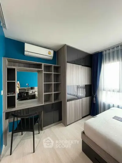 Modern bedroom with stylish furniture and natural light, featuring a built-in wardrobe and sleek desk area.