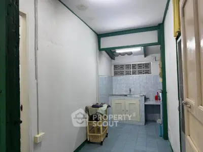 Compact kitchen area with tiled walls and basic amenities in a cozy home setting.
