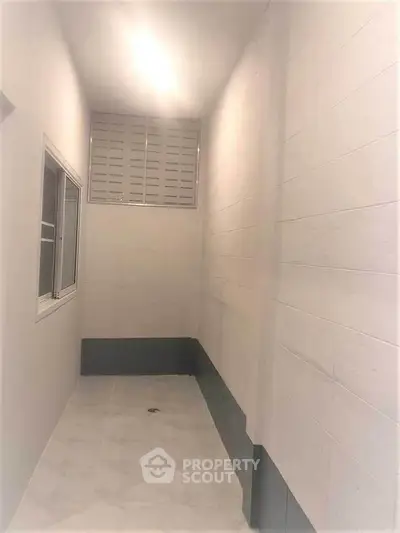 Narrow interior space with tiled floor and window, ideal for storage or utility use.