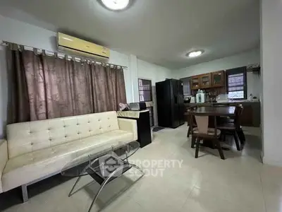 Spacious open-layout living room with modern kitchen and dining area, featuring sleek furniture and ample natural light.
