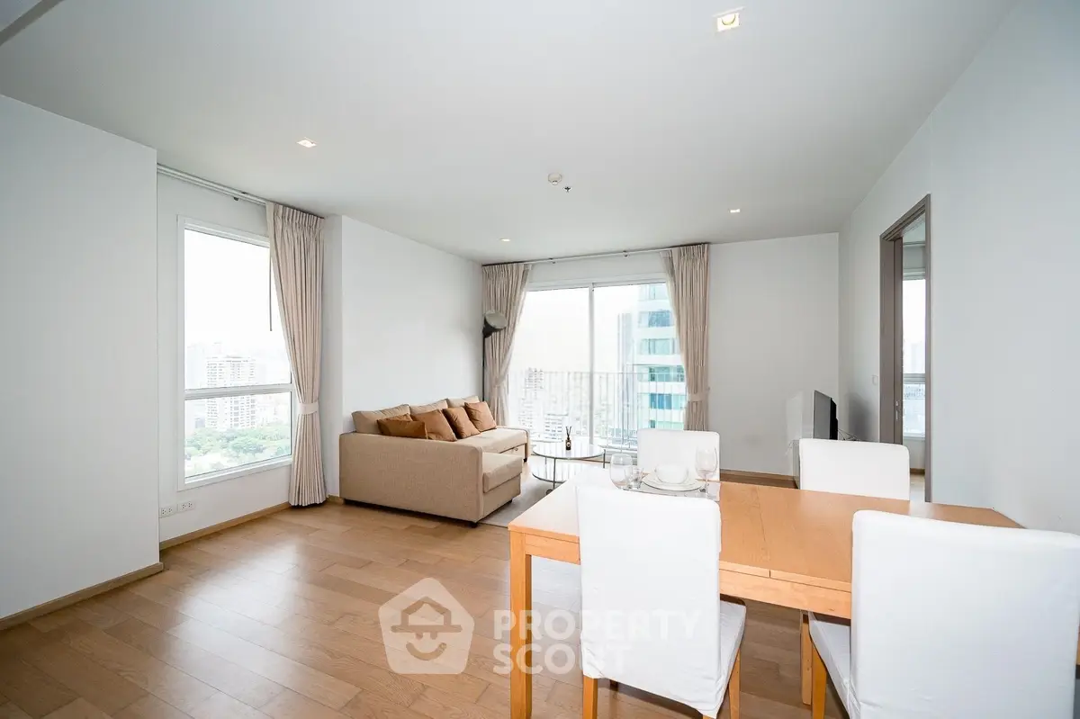 Spacious modern living room with large windows and elegant dining area in a high-rise apartment.