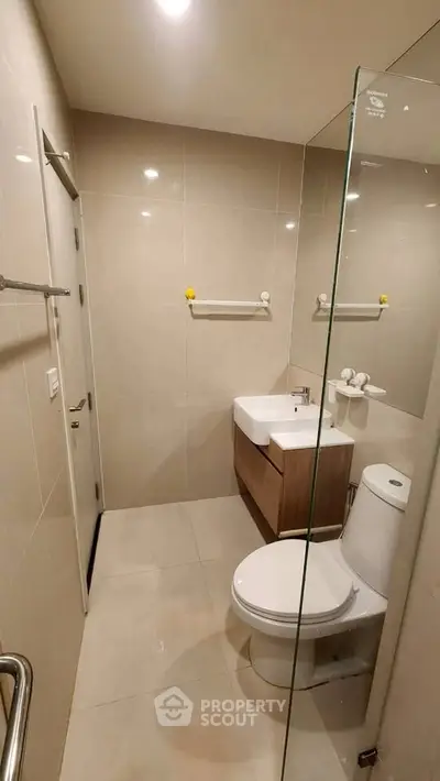 Modern bathroom with sleek fixtures and glass shower partition in a contemporary apartment.