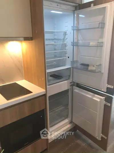 Modern kitchen with built-in fridge and sleek appliances in stylish apartment.