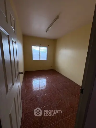 Spacious empty room with tiled flooring and natural light, perfect for customization.