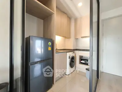 Modern compact kitchen with sleek appliances and stylish cabinetry in a contemporary apartment.