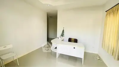 Minimalist home office with white desk and chair, bright natural light, and simple decor.